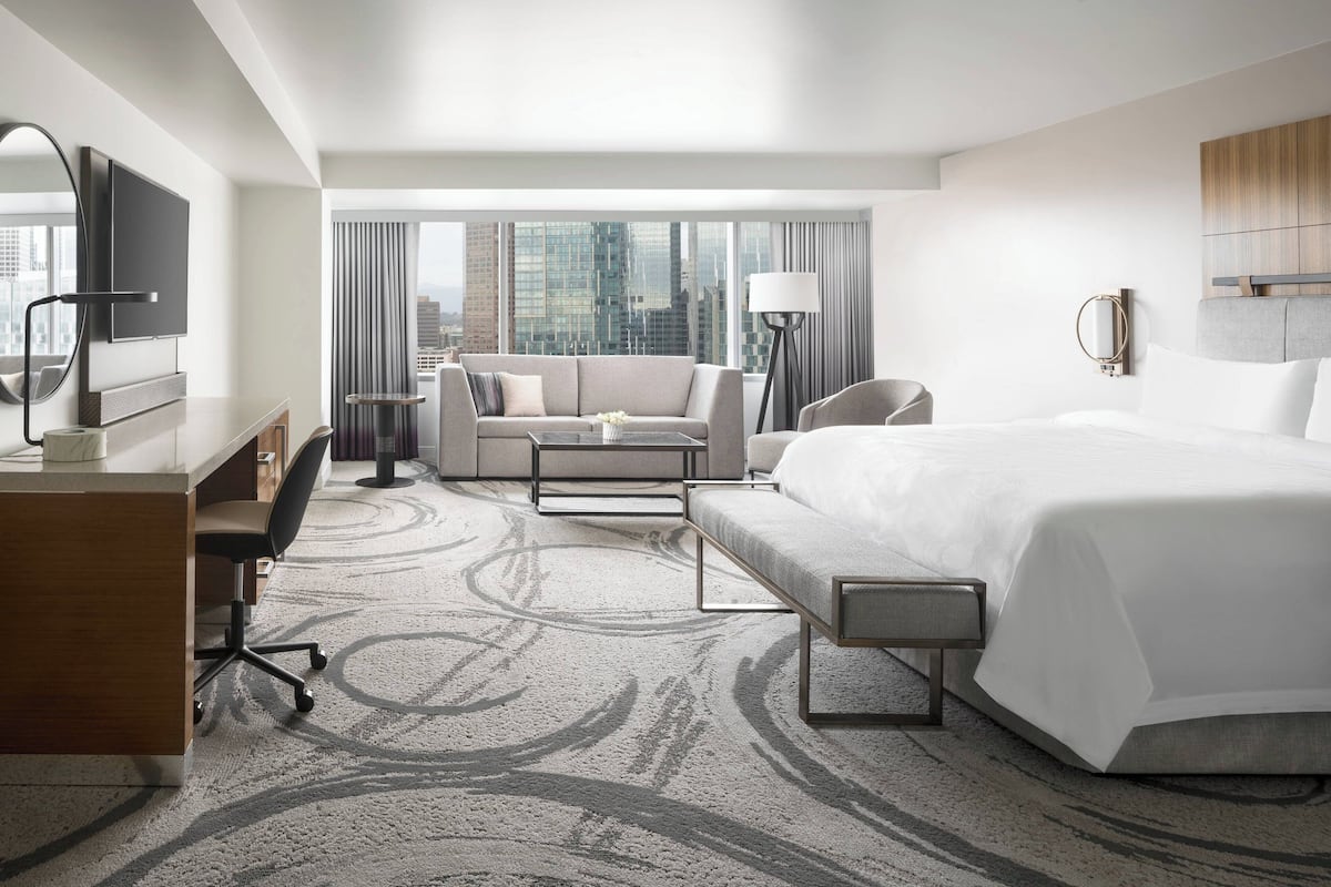 Une chambre d’hôtel moderne avec un grand lit, un bureau avec une chaise, un canapé et une télévision.
