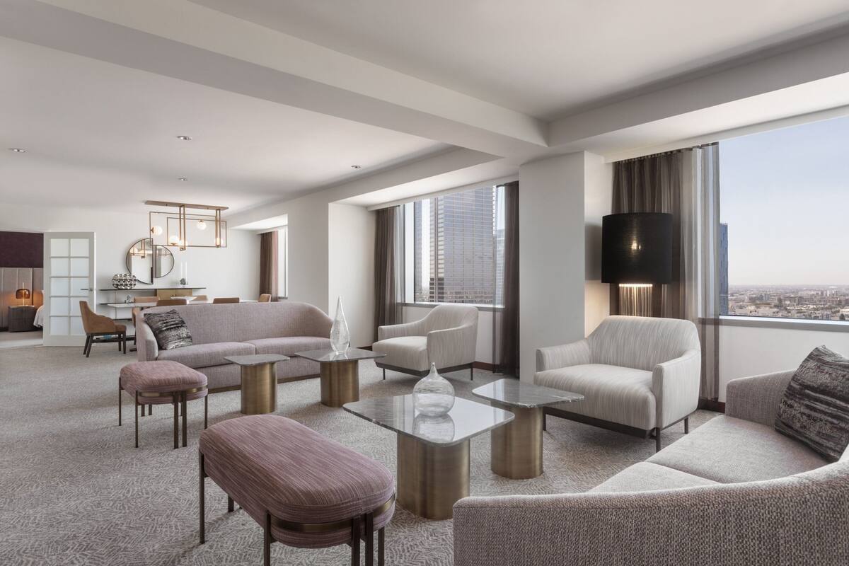 A spacious living room with a city view, modern furniture, and a large flat-screen TV.
