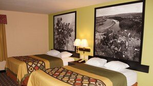 Een hotelkamer met twee bedden, een nachtkastje met een lamp, en twee grote zwart-wit landschapstekeningen aan de muur.