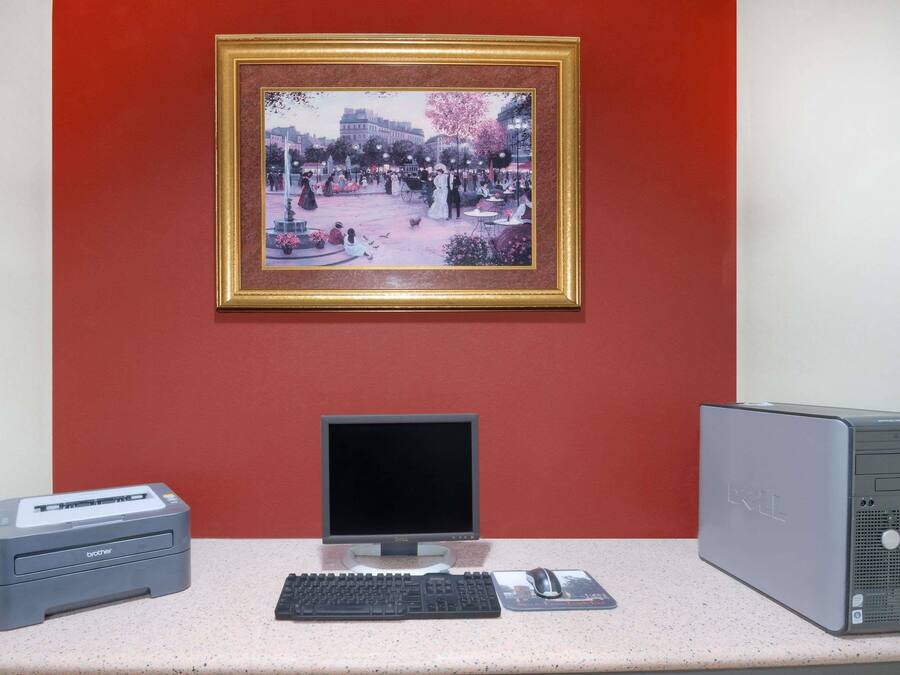 A desktop computer setup with a monitor, keyboard, and mouse on a desk, a printer to the left, and a laptop to the right.