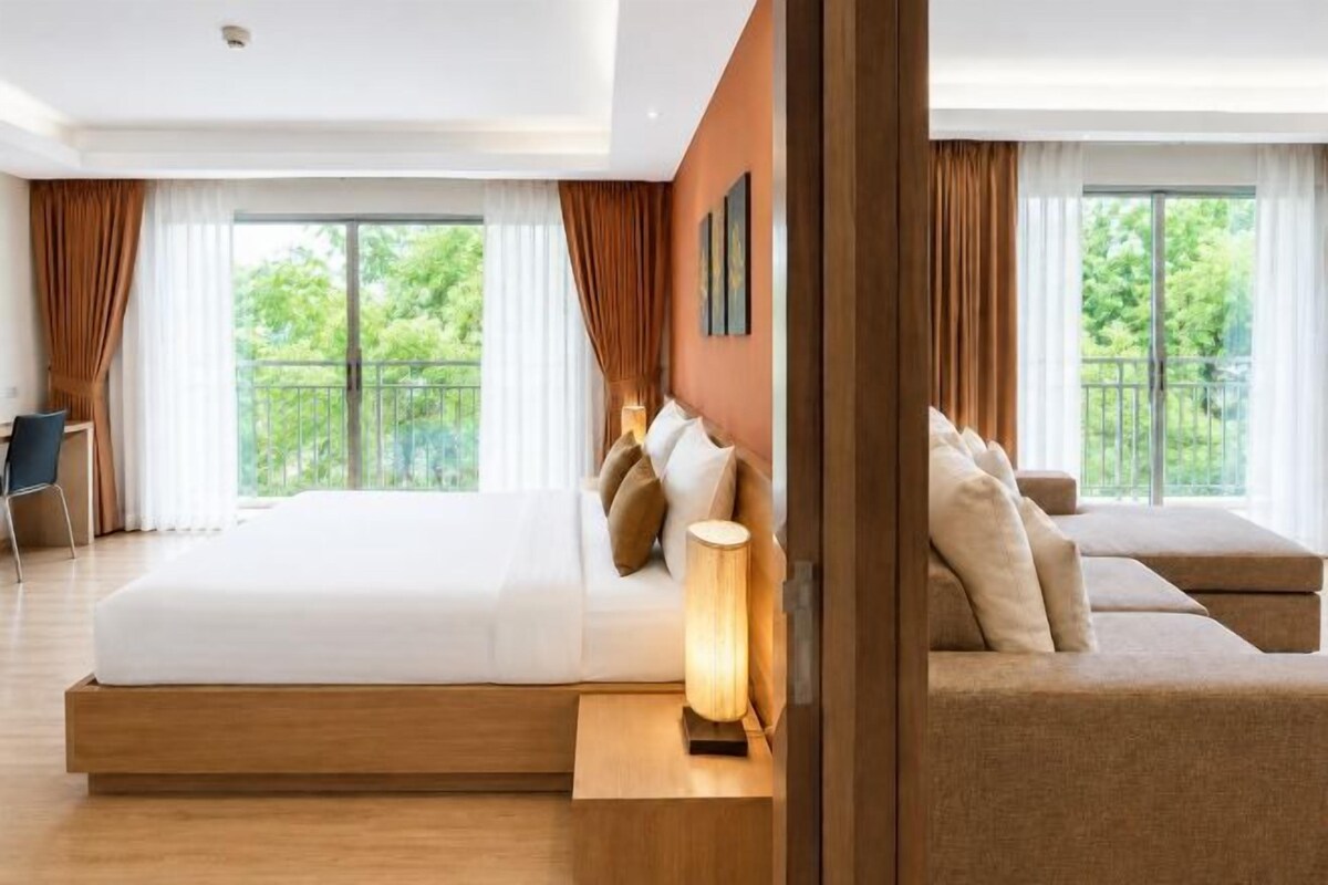 Una camera d'albergo moderna con un ampio letto, un divano, una scrivania e vista sull'esterno.