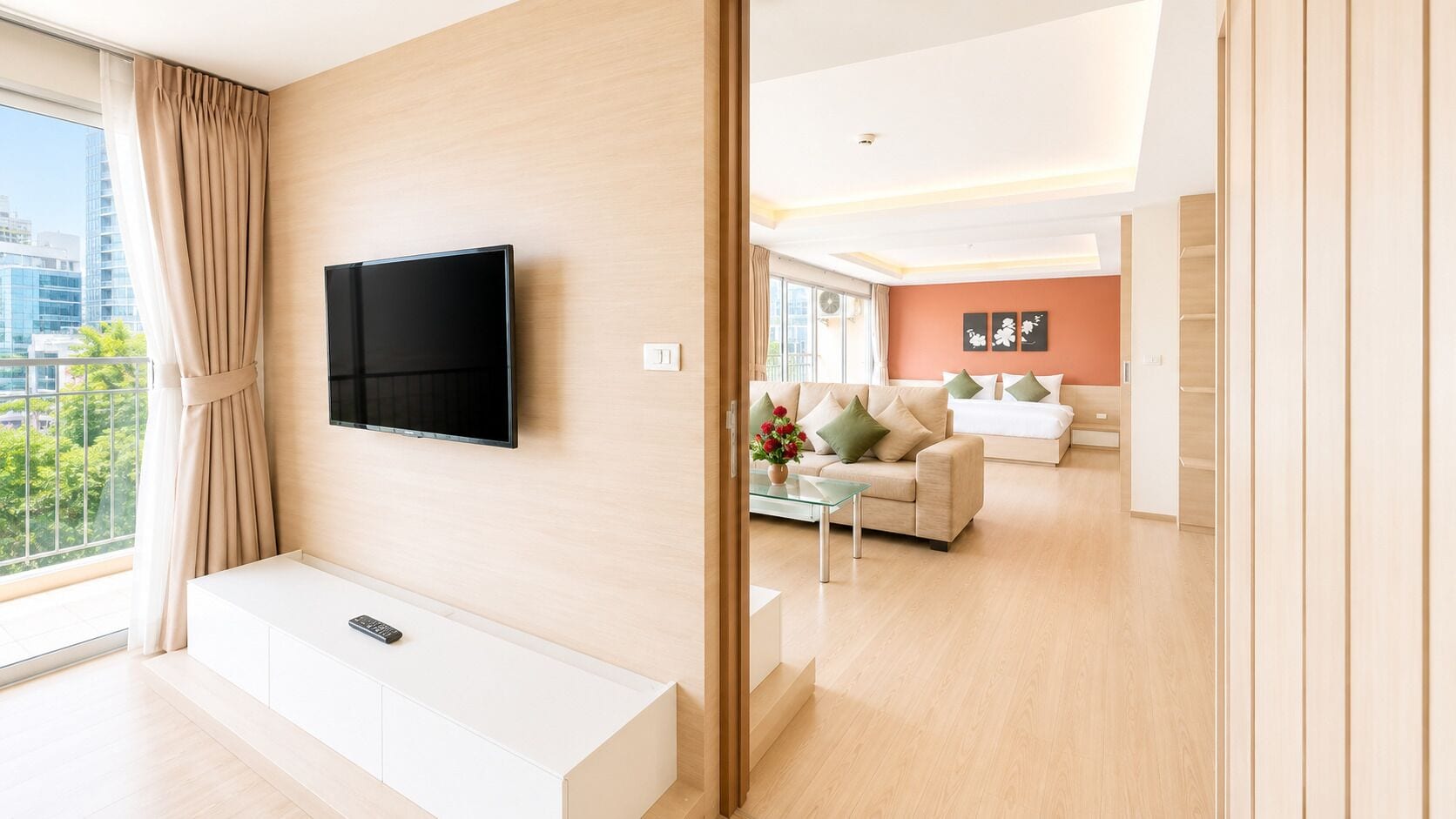 A modern living room with a flat-screen TV, a sofa set, a coffee table, and a large window with curtains.