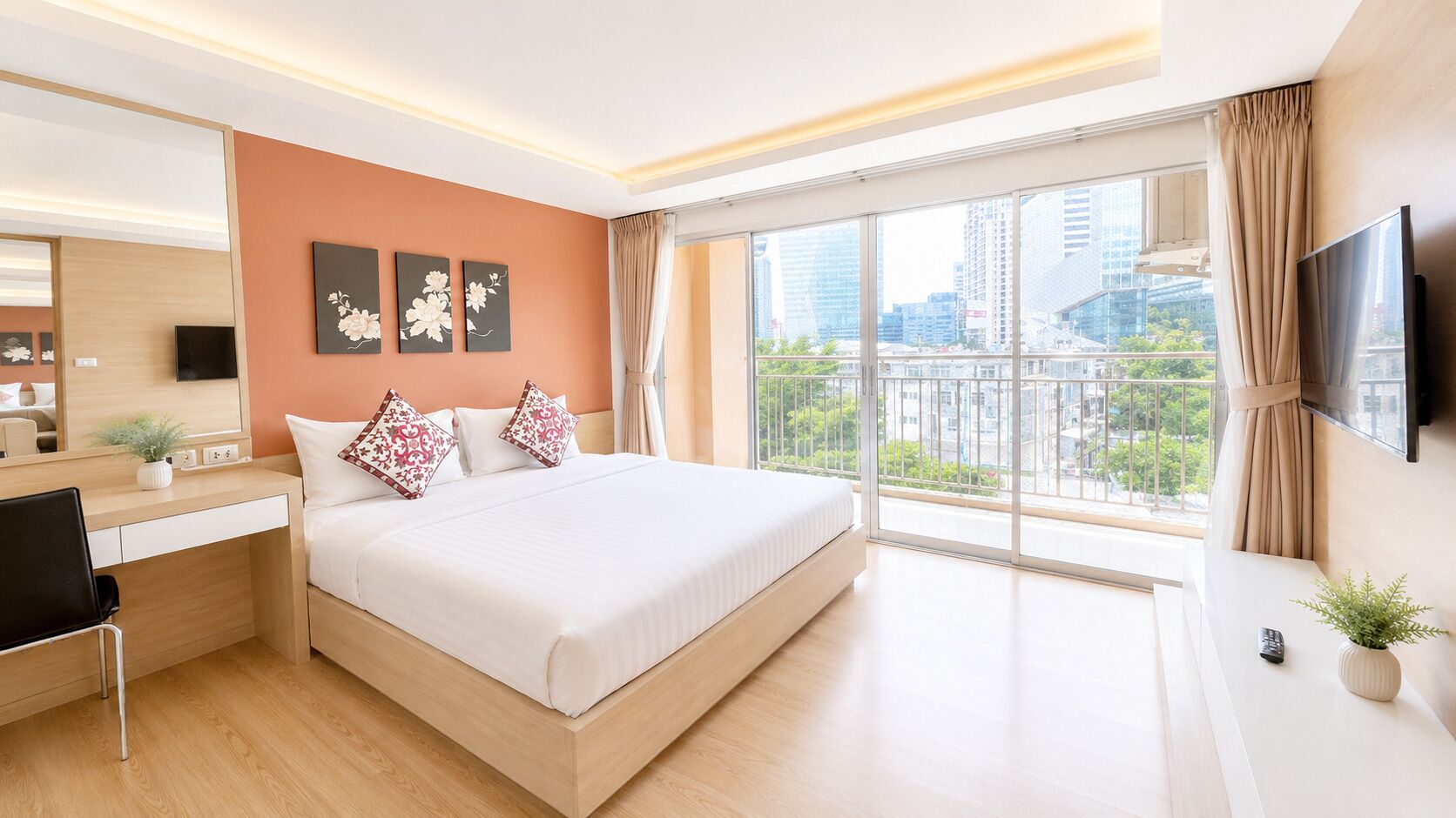 Een hotelkamer met een bed, bureau en groot raam met uitzicht over de stad.