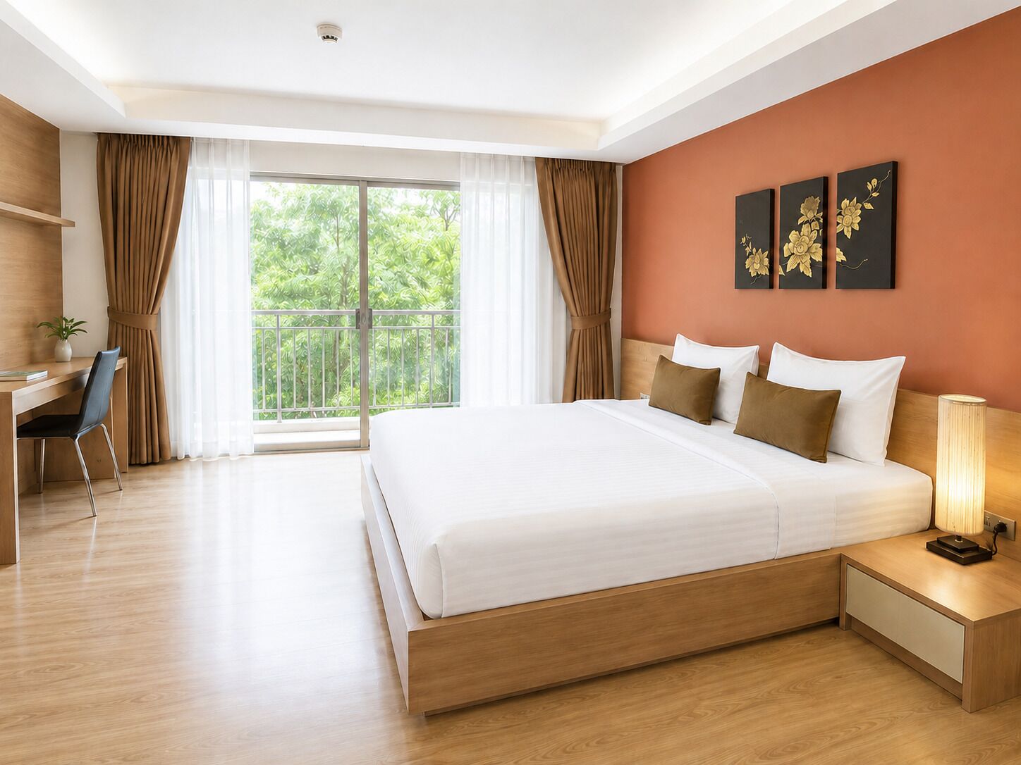 A modern hotel room with a large bed, a desk, and a view of greenery through the window.