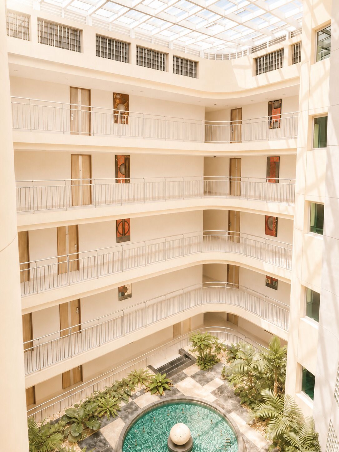 A multi-level atrium with balconies, a central courtyard with a pool, and a glass ceiling.