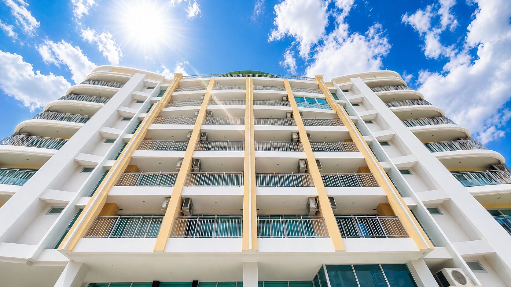 A multi-story hotel with balconies, air conditioning units, and a clear sky.