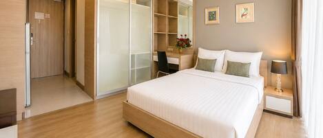 A modern hotel room with a large bed, a desk, a wardrobe, and a mirror.
