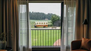 A room with a large window overlooking a grassy area with a wooden structure and a bench.