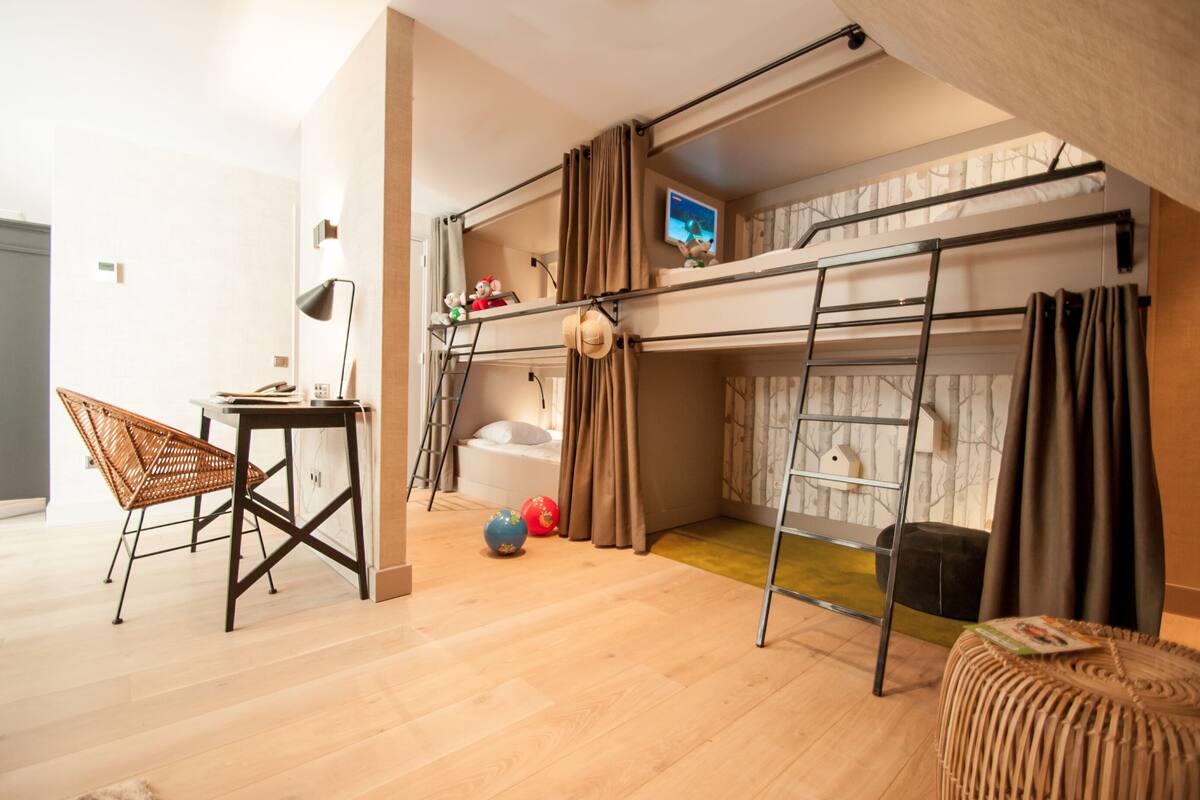 Una habitación con una cama individual superpuesta, un escritorio, una silla y una mesita.