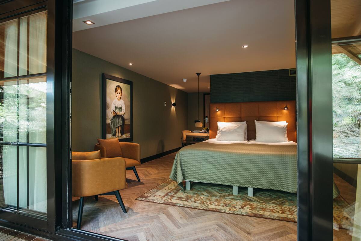 Un dormitorio moderno con una cama grande, una silla, una mesita de noche y un cuadro en la pared.