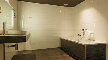Ein modernes Badezimmer mit Waschtisch, Badewanne und Duschbereich.