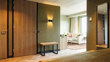 Een moderne hotelkamer met een groot bed, een houten garderobe, een klein tafeltje en een zithoek met een bank en een salontafel.