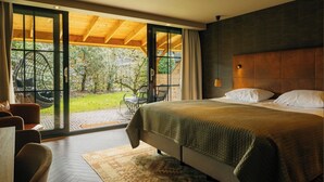 A bedroom with a large bed, a wooden ceiling, and a sliding glass door leading to a patio with outdoor furniture.