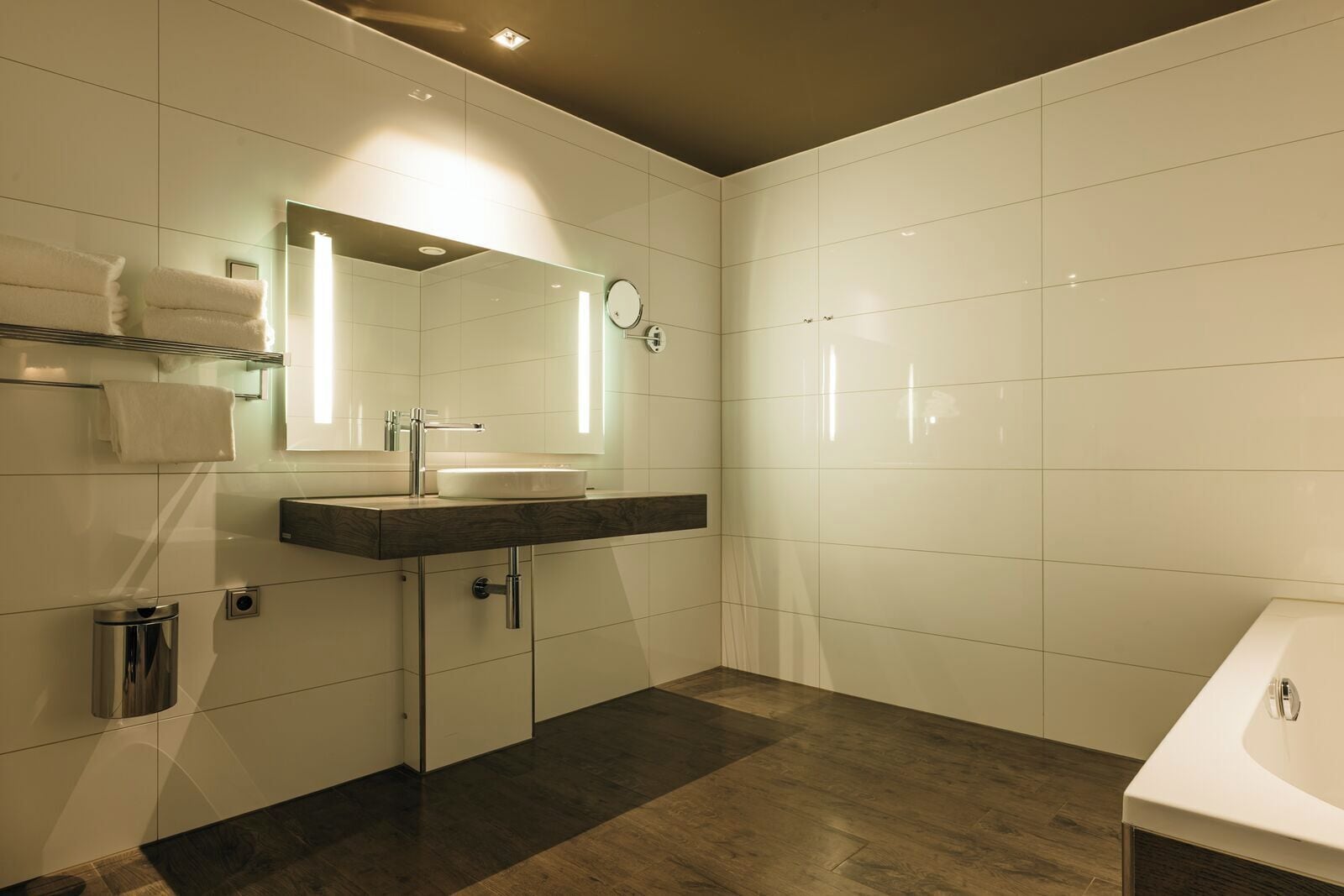Een moderne badkamer met een wastafel, een wasbak, een spiegel, een handdoekrek en een toilet.