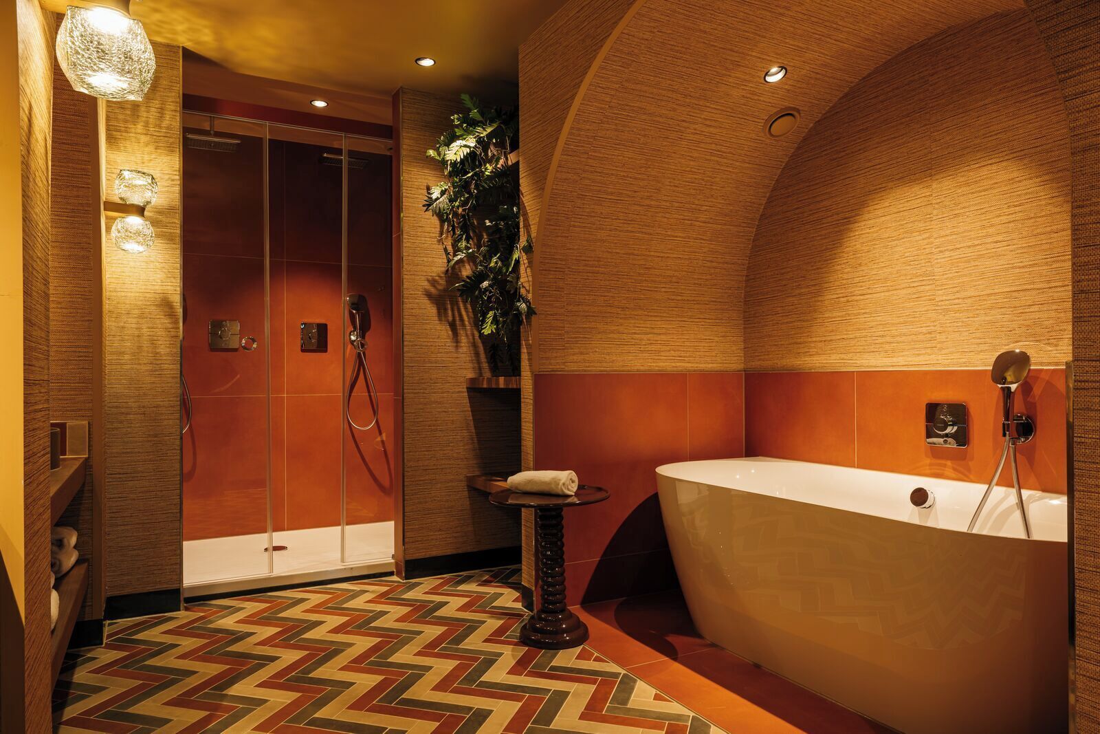 A modern bathroom with a large bathtub, a shower area, and a patterned floor.