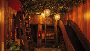 A wooden interior with a wooden staircase, a small table with a lantern, and a plant.