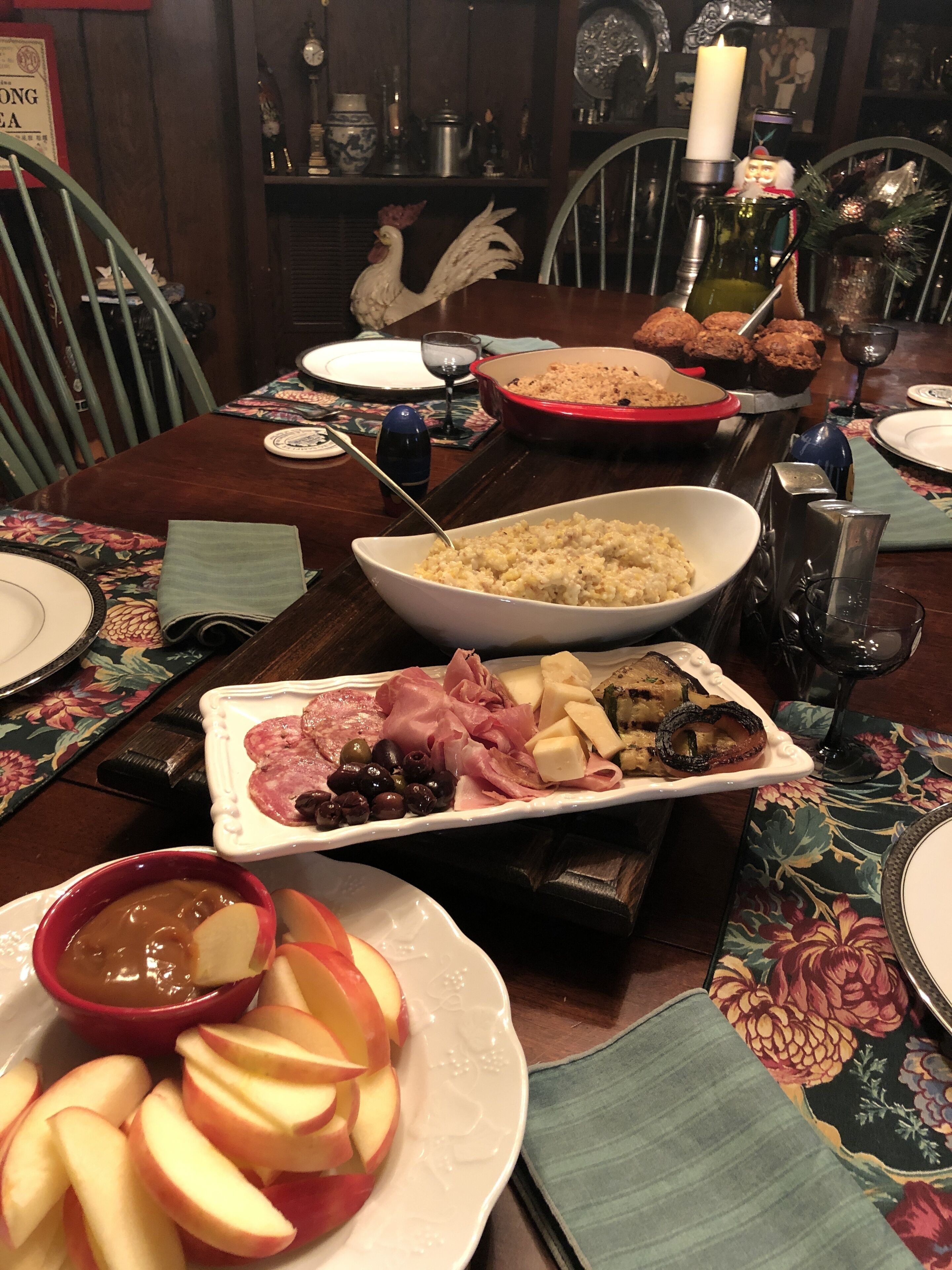 Ein Esstisch, reichhaltig gedeckt mit verschiedenen Speisen, darunter Reis in einer Schüssel, Fleisch auf einem Teller und eine Schüssel Äpfel.