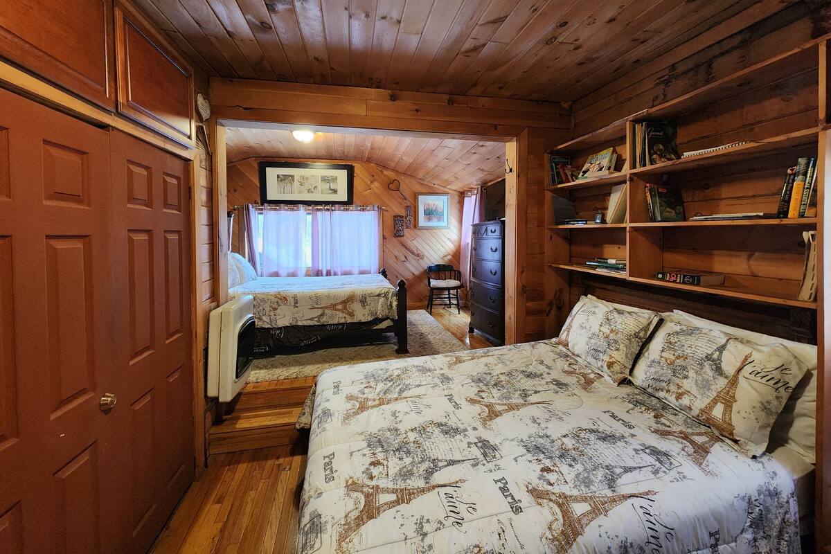 Ein gemütliches Blockhauszimmer mit einem großen Bett, einem Schminktisch und einem Bücherregal.