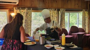 A chef preparing food at a buffet table with various dishes and condiments.