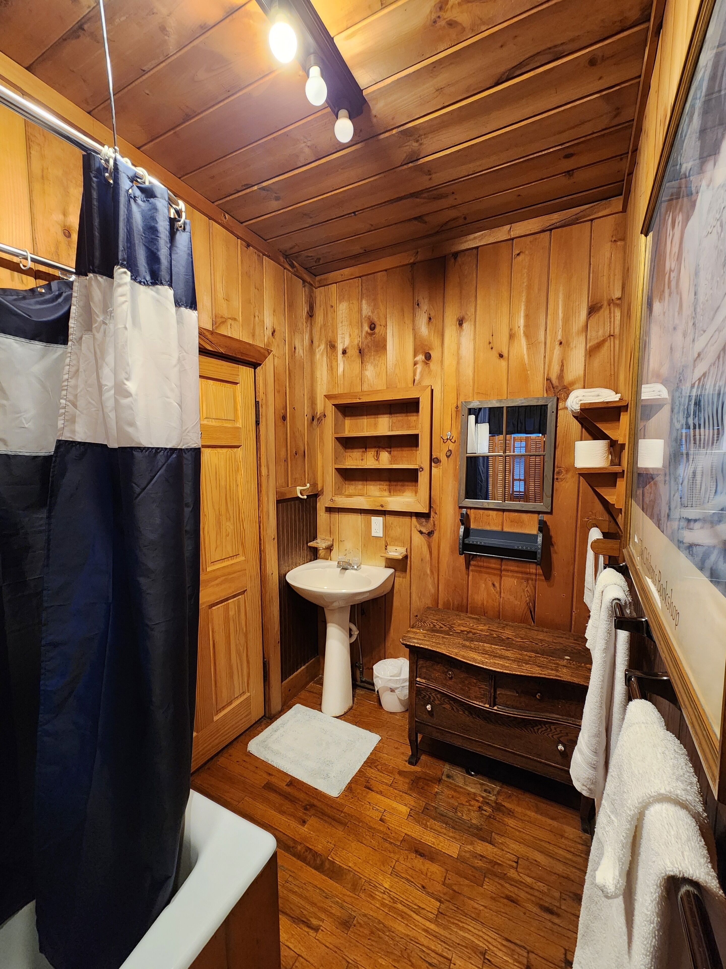 A wooden bathroom with a sink, shelves, and a bench.