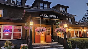 A two-story building with a sign reading "LAKE HOUSE" above the entrance. There are hanging flower baskets and a neon sign on the left side.