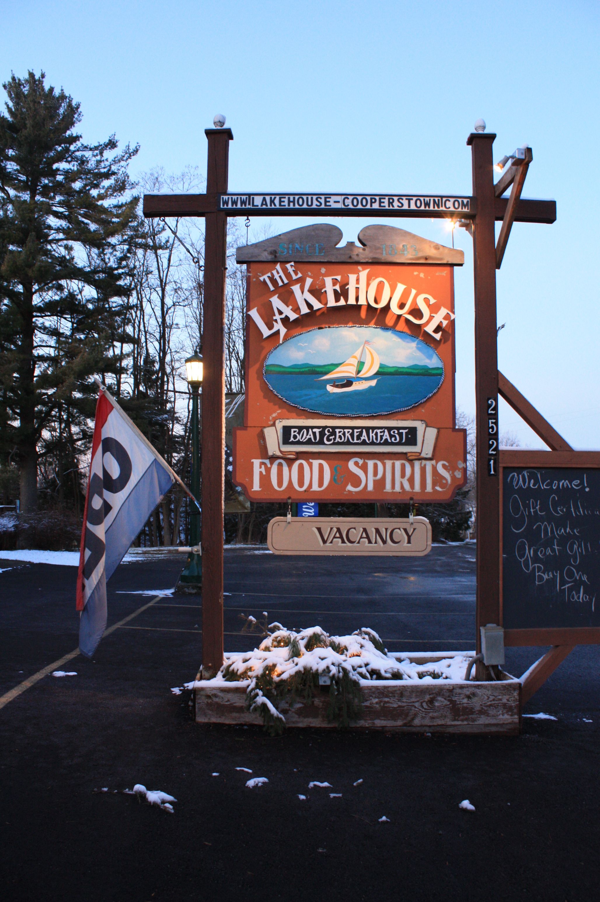 A sign for The Lakehouse with a boat and sailboat illustration, indicating it offers boat & breakfast, food & spirits, and is currently vacant.