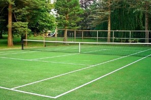 A tennis court with a net, surrounded by trees. - Rock Hall Luxe Lodging (Winsted)