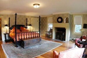 A bedroom with a four-poster bed, a fireplace, and a large window. - Rock Hall Luxe Lodging (Winsted)