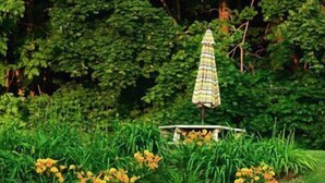 A swimming pool with clear water, surrounded by lush greenery and yellow flowers. - Rock Hall Luxe Lodging (Winsted)