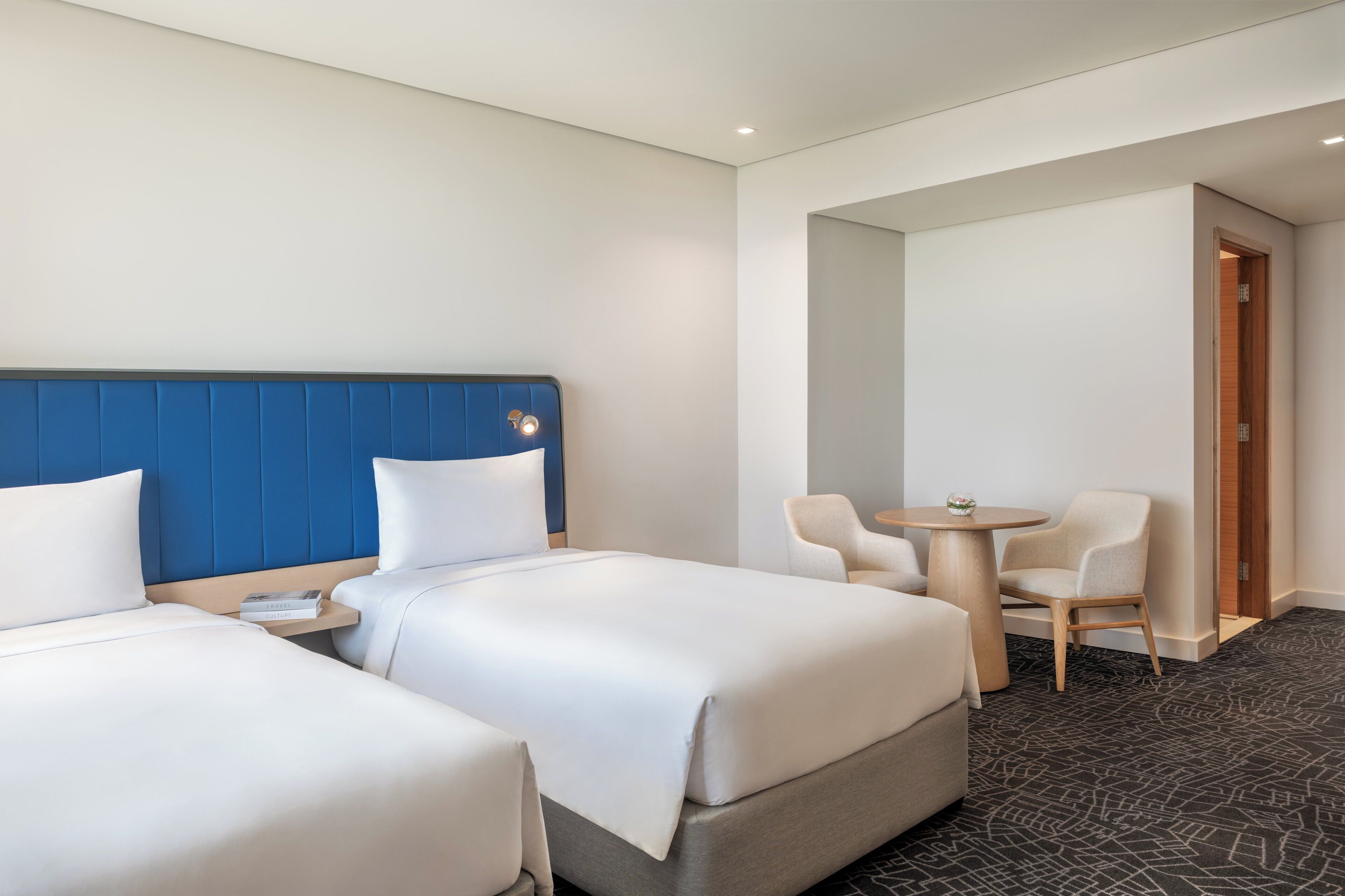 A hotel room with two beds, a small table, and two chairs.