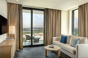 A hotel room with a sofa, a coffee table, a TV, and a view of a cityscape through large windows. - Yas Plaza Bay (Abu Dhabi)
