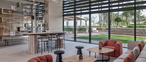 Un interior moderno con una zona de bar, asientos y grandes ventanales que ofrecen vistas al exterior.