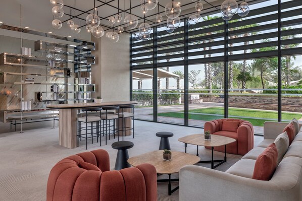 Un interior moderno con una zona de bar, asientos y grandes ventanales que ofrecen vistas al exterior.