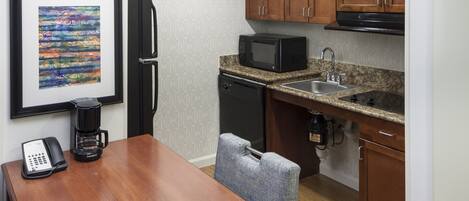 A compact kitchen with wooden cabinets, a microwave, a sink, and a coffee maker.