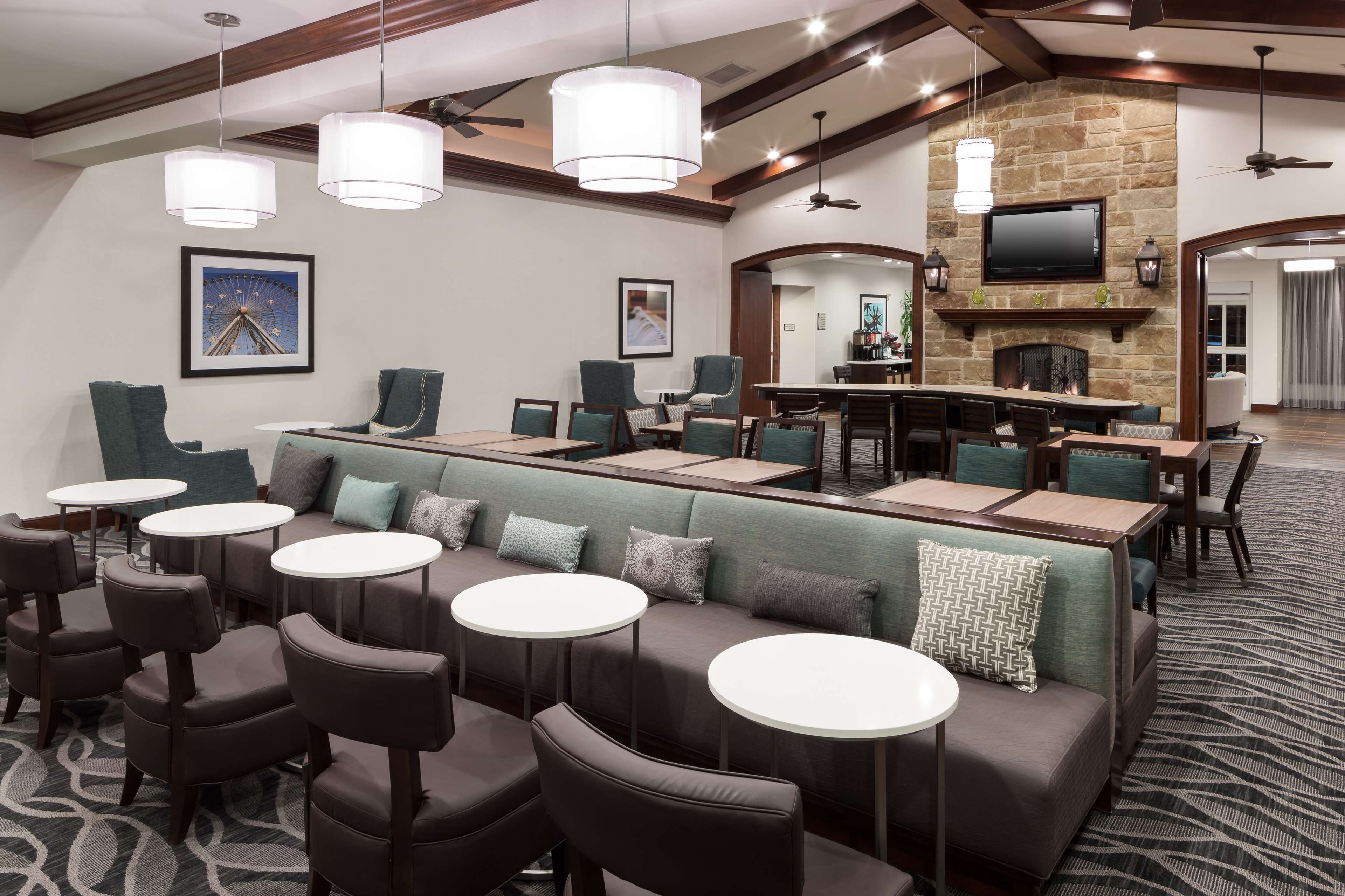 A hotel lobby with a bar area, seating arrangements, and a television mounted on the wall.