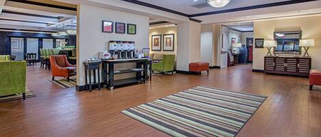 Um hall amplo com espaço para café, área de estar e balcão de recepção.