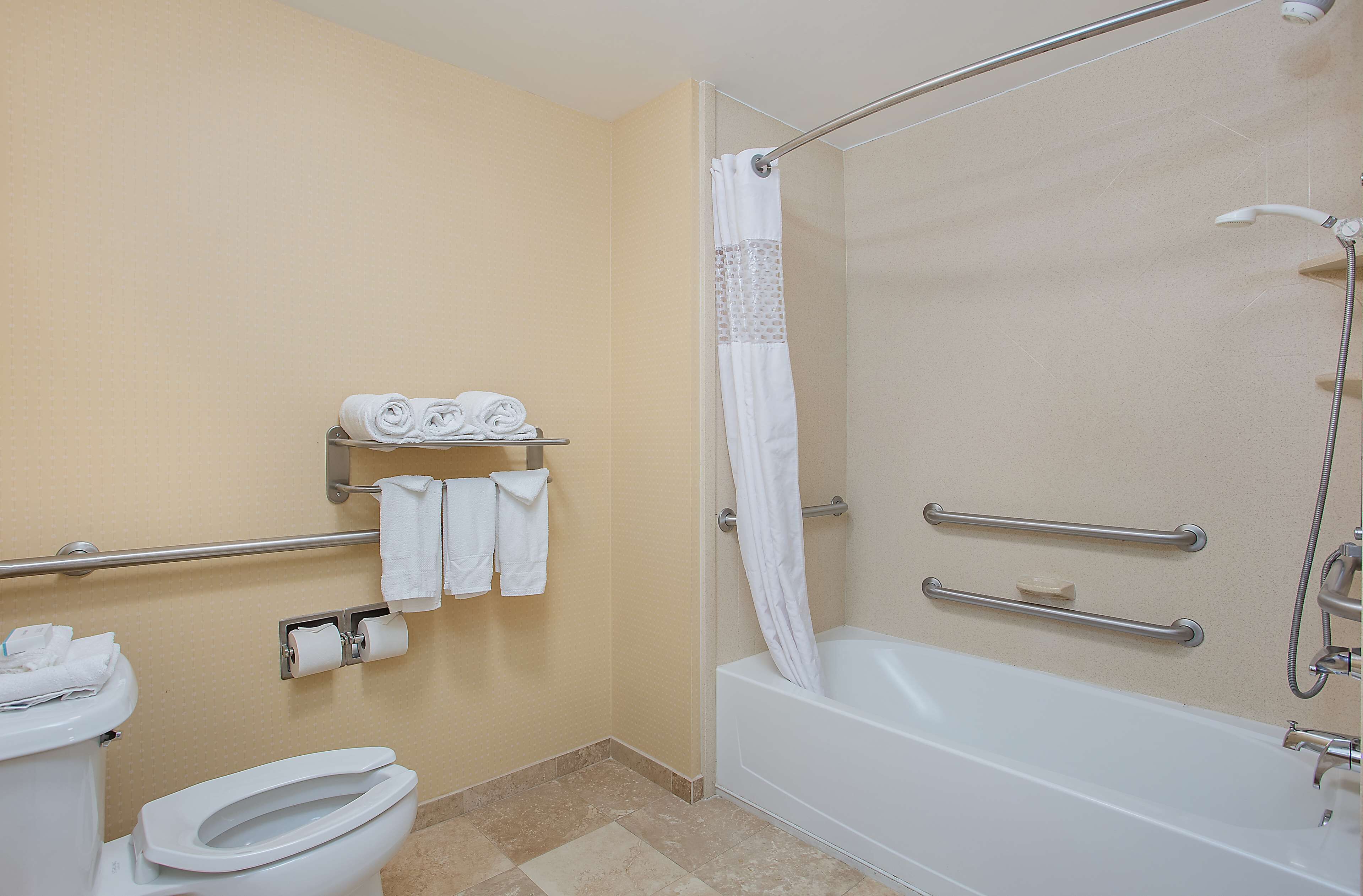 A bathroom with a toilet, a shower with a glass door, and a bathtub. There are towels and a soap dish on the wall.