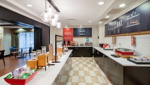 Un'area cucina moderna con pavimento a scacchi, un lungo bancone con diversi oggetti e un menù alla lavagna appeso al muro.