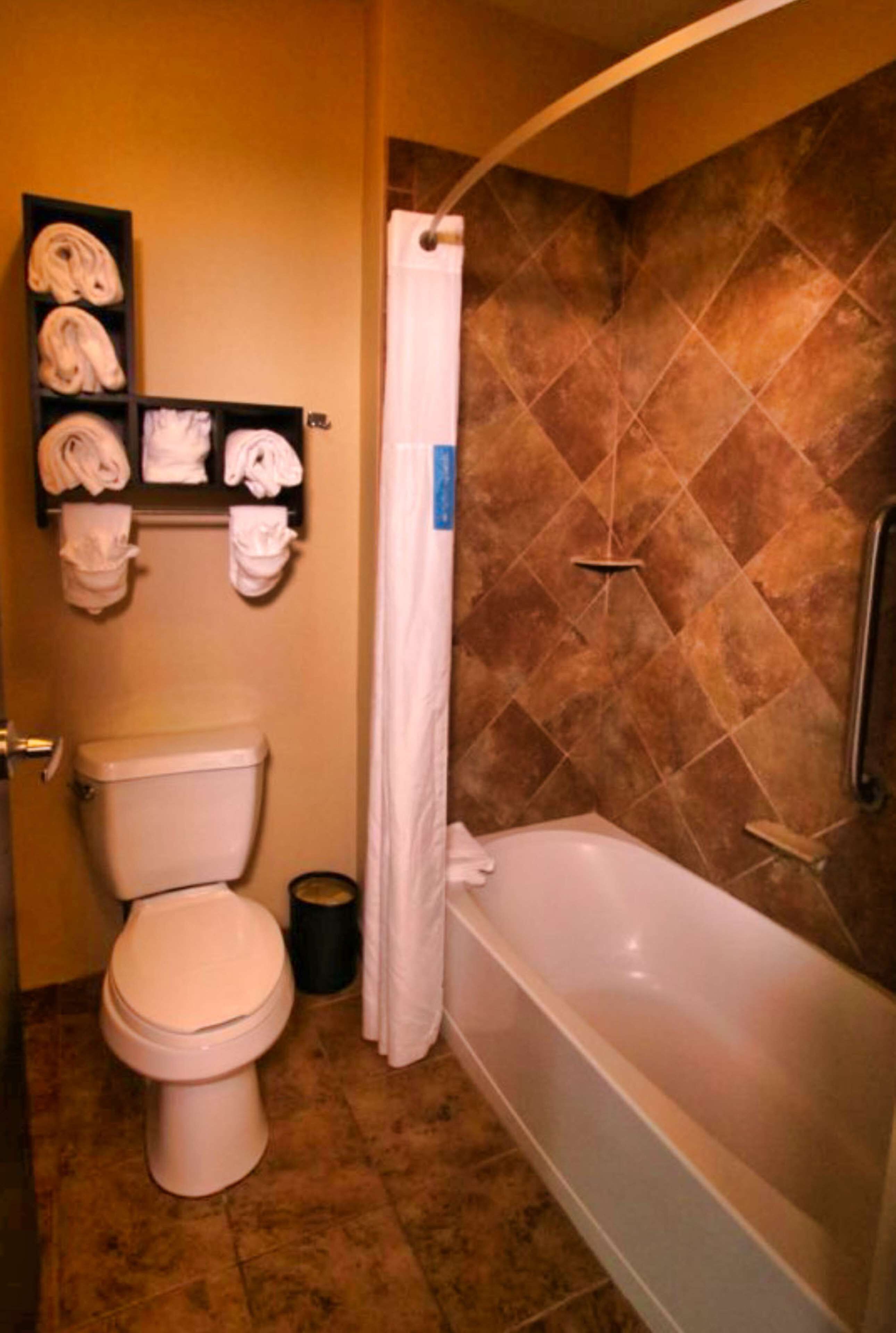 A bathroom with a toilet, a bathtub, and a shelf with towels.