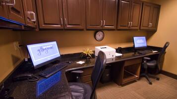A workspace with two desks, each with a computer and keyboard, a clock on the wall, and a printer.