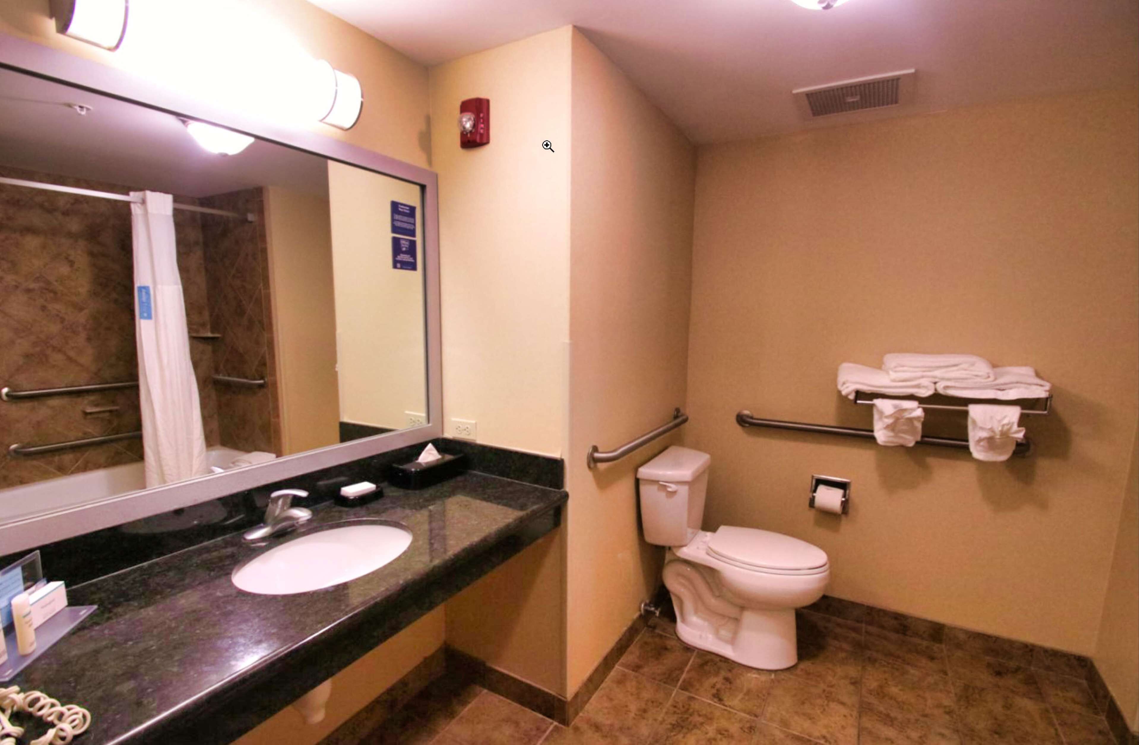 Un bagno con lavandino, specchio, WC e porta asciugamani.