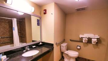 Un baño con lavamanos, espejo, inodoro y barra para toallas.