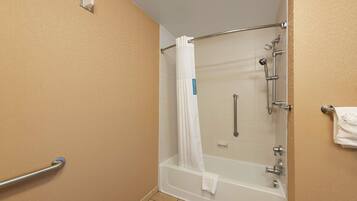 A shower area with a bathtub, a handrail, and a towel rack.