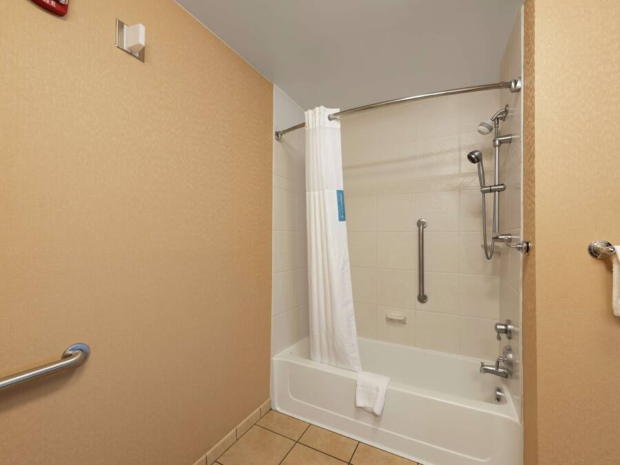 A shower area with a bathtub, a handrail, and a towel rack.