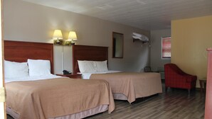 A hotel room with two beds, a red chair, a nightstand, and a lamp. - Motel Reedsburg (Reedsburg)