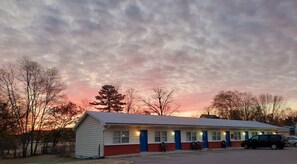 A motel with a row of rooms, each with a door and windows.