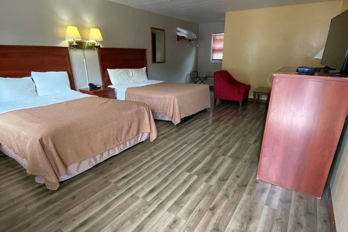 A room with two beds, a desk, a chair, and a mirror.