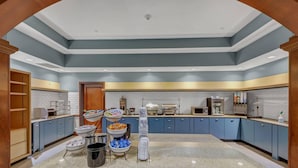 A modern kitchen with blue cabinets, a granite countertop, and various food items on the counter. - Country Inn & Suites by Radisson, Braselton, GA (Hoschton)