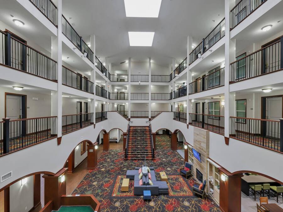 A multi-level hotel lobby with a central staircase, multiple balconies, and a carpeted floor.