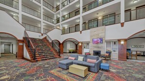 A multi-level hotel lobby with a staircase, seating area, and a flat-screen TV. - Country Inn & Suites by Radisson, Braselton, GA (Hoschton)